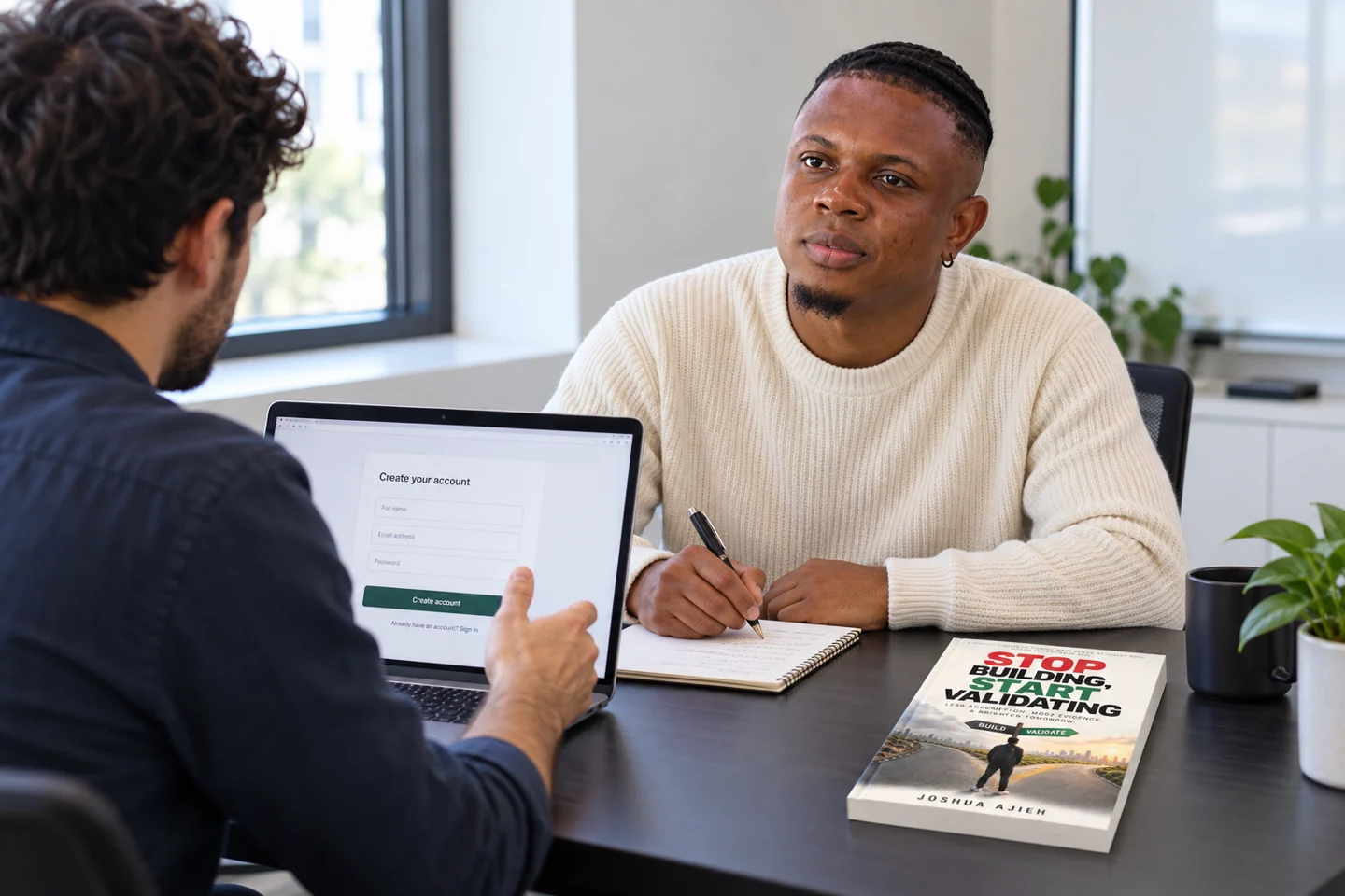 Joshua Ajieh observes a man using a signup form on a laptop, with Stop Building, Start Validating on the desk.